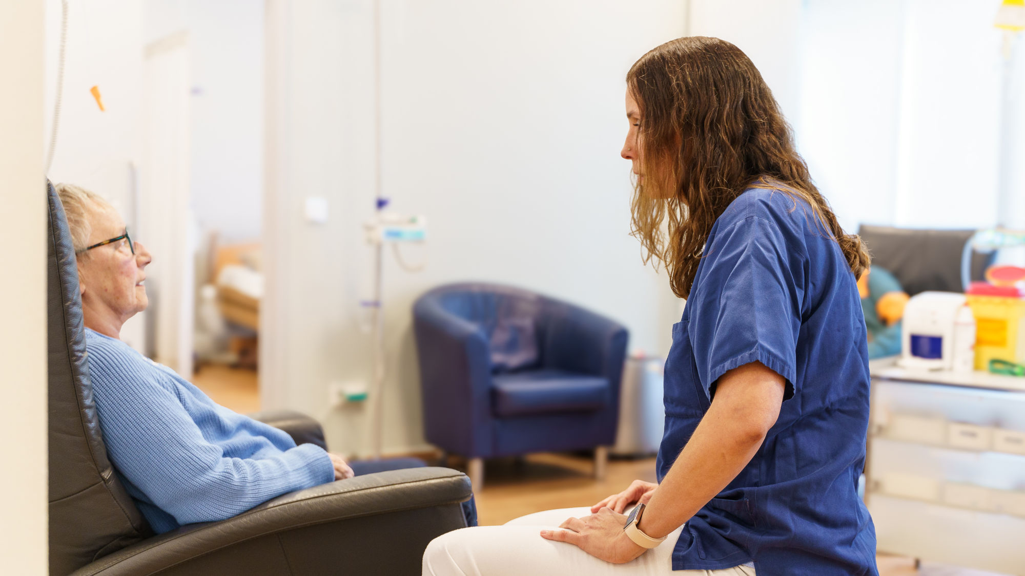 Pflegeleitung begleitet eine Patientin während der Therapie und erkundigt sich nach ihrem Befinden.