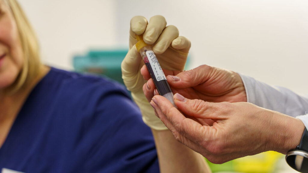 Übergabe einer Blutprobe zwischen Laborantin und Arzt