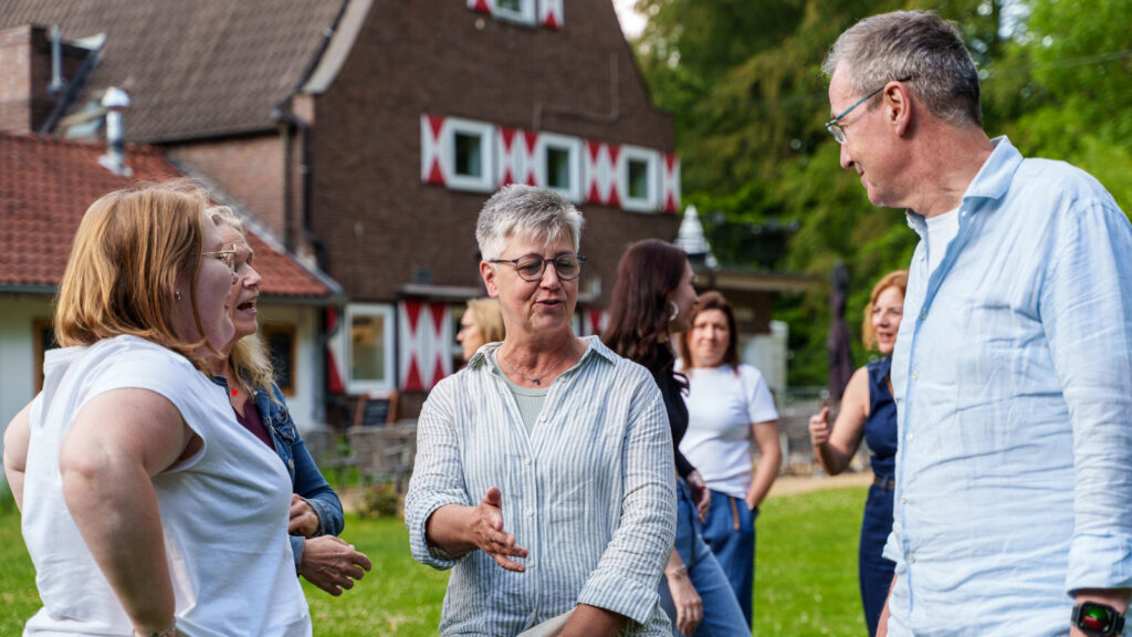 Mitarbeitende der Onkologie Münster im Gespräch im Garten der Gaststätte